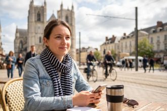Femme détendue dans un café nantais avec cathédrale en arrière-plan
