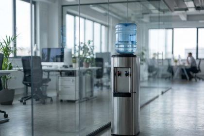 Fontaine à eau en inox installée dans un open space moderne avec cloisons en verre et plantes d'intérieur