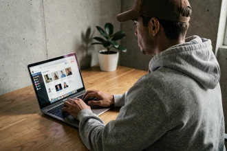 Personne anonyme tapant sur un ordinateur portable dans un bureau minimaliste, illustrant la notion d'identité numérique cachée et de pseudonyme en ligne